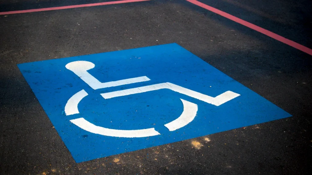 Blue and white painted disabled parking symbol on a dark asphalt road surface.