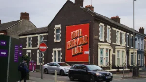 Liverpool terrace housing featuring a prominent red mural with You'll Never Walk Alone text.