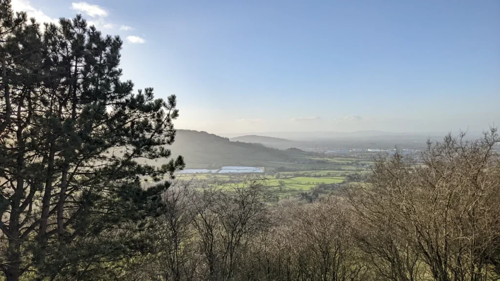 A panoramic view of a lush green valley in the United Kingdom under a bright sky.