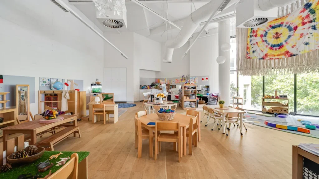 Spacious, modern learning hub with wooden furniture and large windows overlooking green woods.
