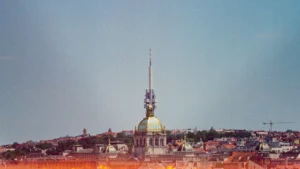 Cityscape skyline under a clear sky with a stylized fire overlay at the bottom.