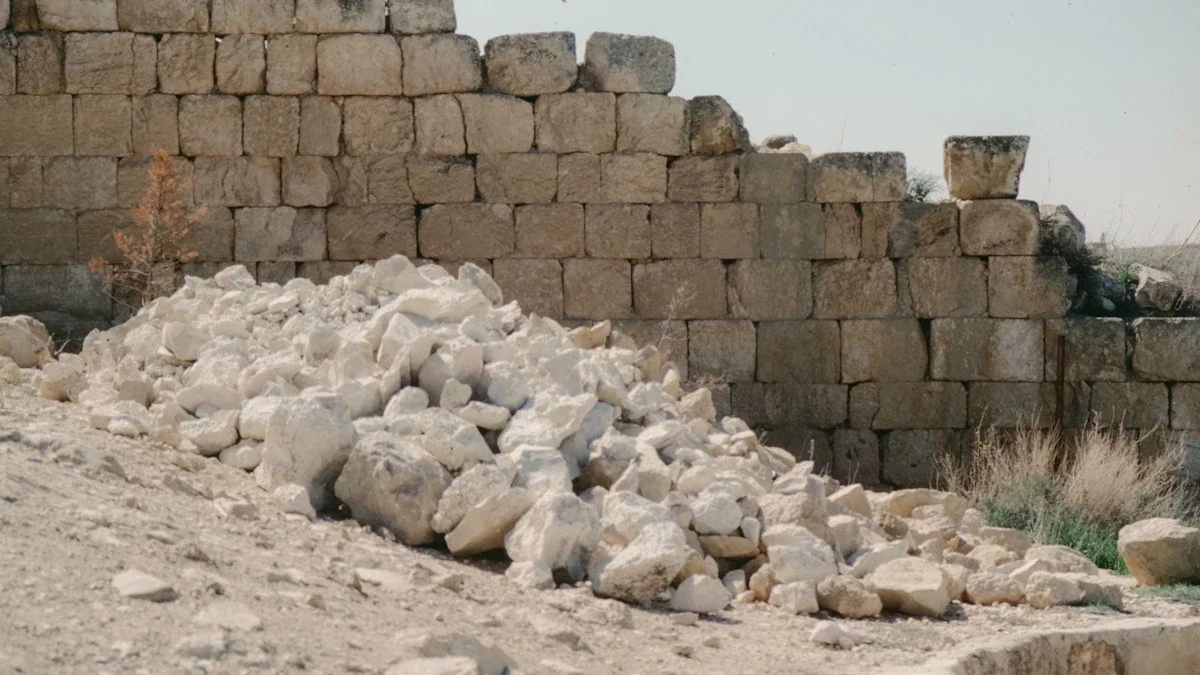 A pile of white limestone rocks placed against a weathered stone wall.