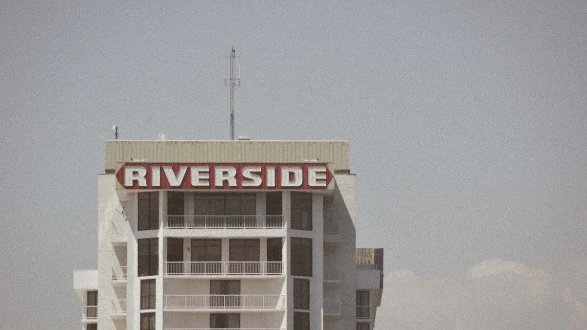 The top of a tall white building with a prominent Riverside sign attached.