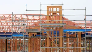 Construction cranes tower over a large-scale residential development project under a blue sky.