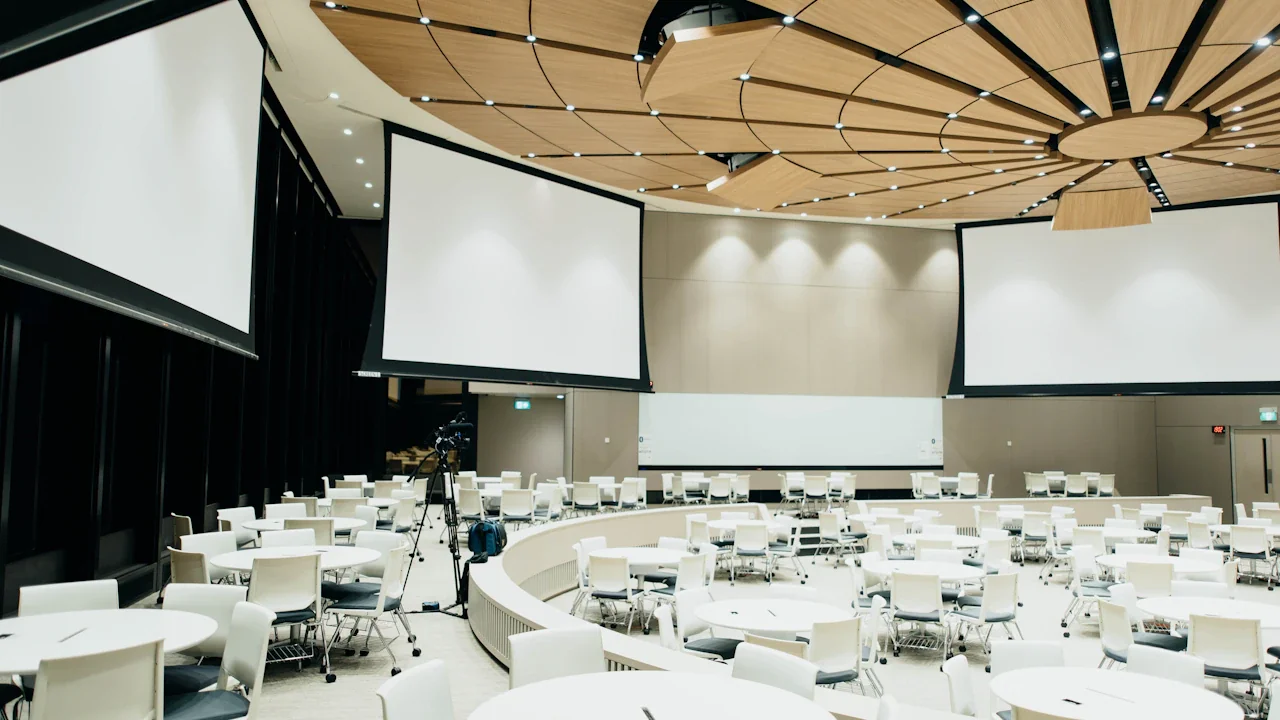 A professional empty conference room setting with multiple projection screens for official presentations.