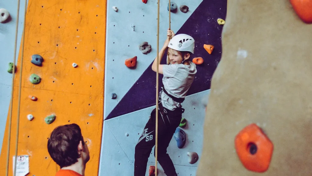 Young boy wearing a helmet climbing an indoor wall at a leisure centre.