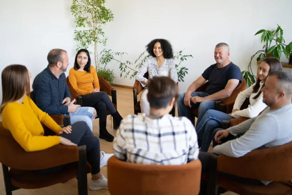 Diverse group of adults sitting in a circle for a supportive group therapy session.