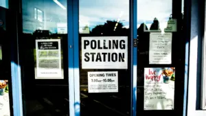 Polling station sign on a glass door of a local community building.