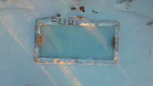 Aerial view of an outdoor ice skating rink in a snowy park setting.
