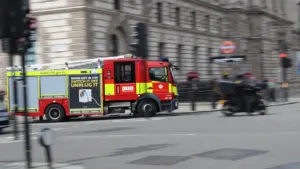 London Fire Brigade truck driving through a busy city street in London.