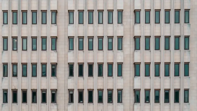 A grey, imposing concrete government office building viewed in daylight.