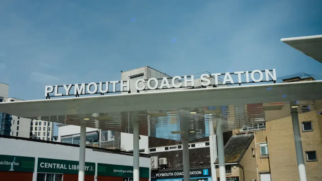 The exterior sign of the Plymouth Coach Station under a clear blue sky.