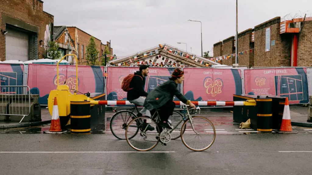 Two people cycling on a city street in Liverpool with temporary event barriers.