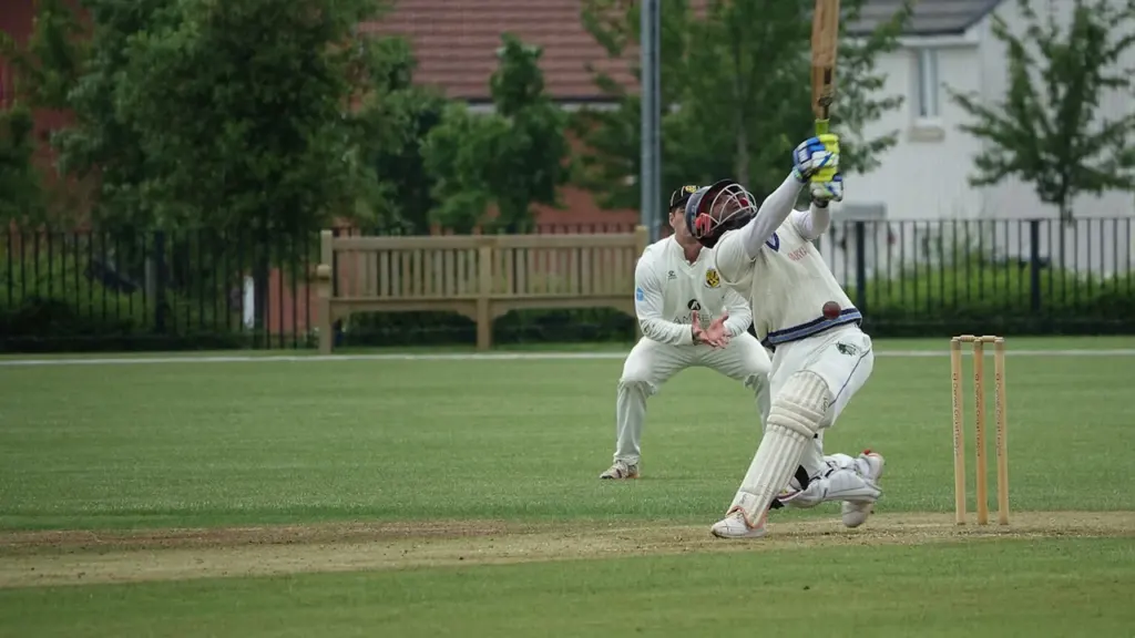 Cricketer in white uniform hitting a ball during a match in Oxfordshire, England.