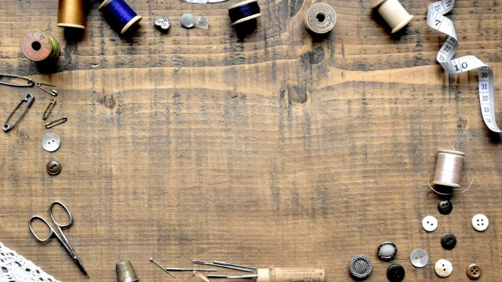 Antique wooden table arranged with vintage sewing supplies like thread, buttons, and scissors.