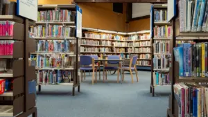 Rows of bookshelves and seating in a quiet public library interior setting.
