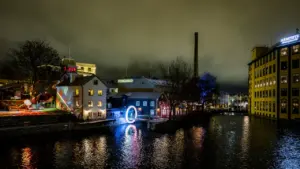 Illuminated urban waterfront at night with artistic light installations and reflection in Leeds.