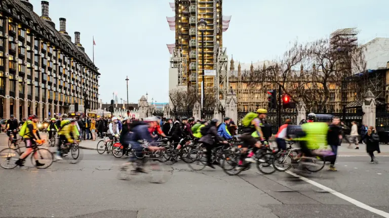 Cyclists riding through busy London intersection with Big Ben in the background.