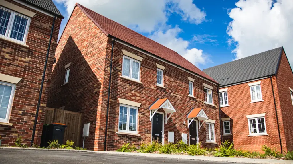 Modern red brick terraced housing estate in the United Kingdom under a blue sky.