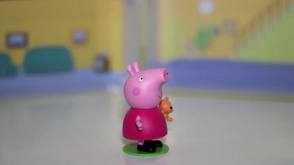 Peppa Pig figurine holding a toy, displayed against a cartoon-themed background.