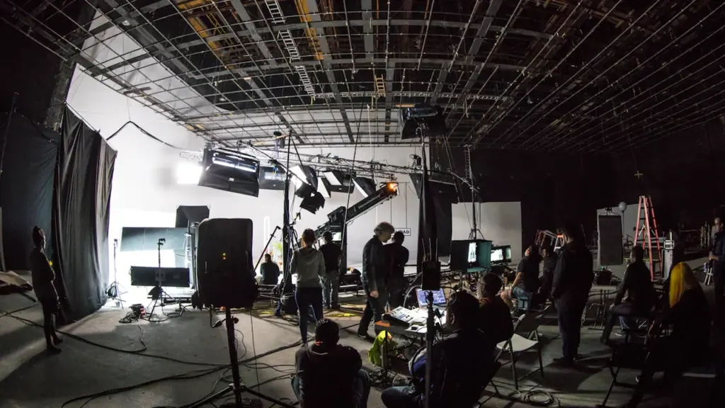 Students learning filmmaking on a professional studio set with camera equipment and lighting.