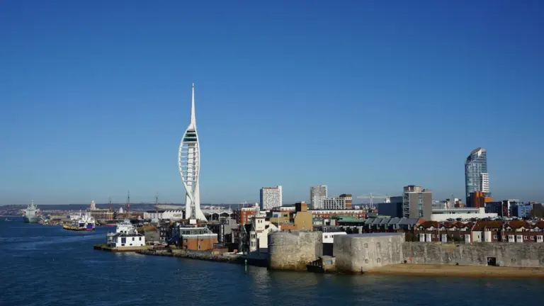 Modern Spinnaker Tower and historic Portsmouth harbor buildings under a clear blue sky.