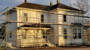 Large historic white building encased in exterior scaffolding during restoration works.