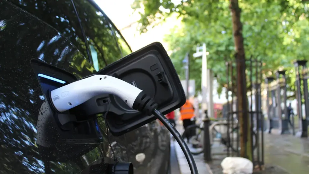 An electric vehicle charging at an outdoor street-side charging point in the city.