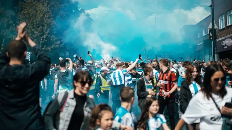 Football fans in team colors walking together on a street in the UK.