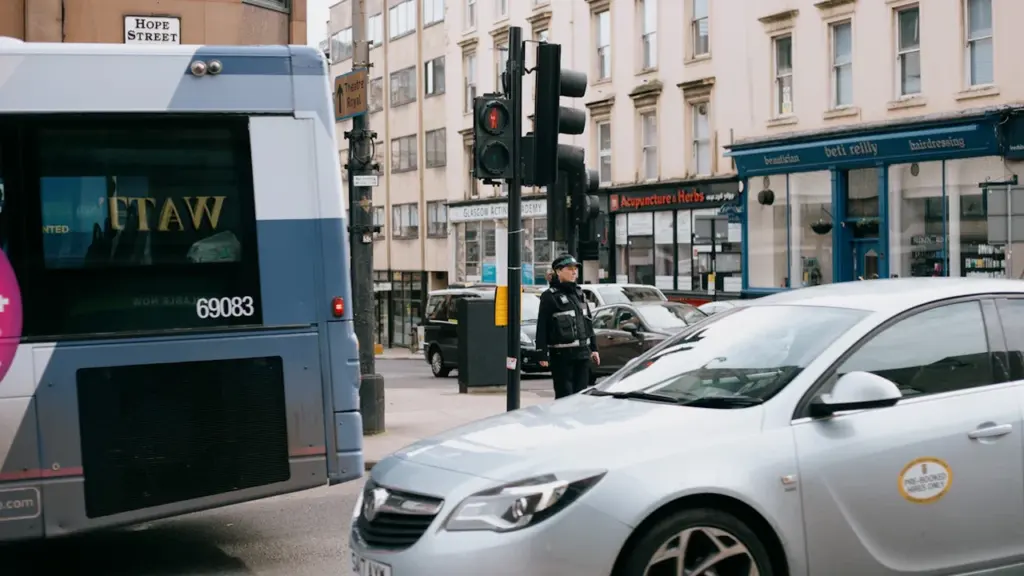 A police officer stands on a Glasgow street near a bus.