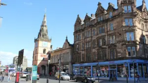 Classic Glasgow street scene featuring a prominent clock tower and historic stone buildings.