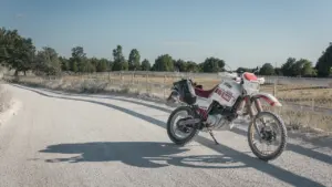 An adventure motorcycle parked on a quiet, rural dirt road in the countryside.