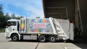 Modern white municipal garbage truck parked at a depot facility in bright daylight.